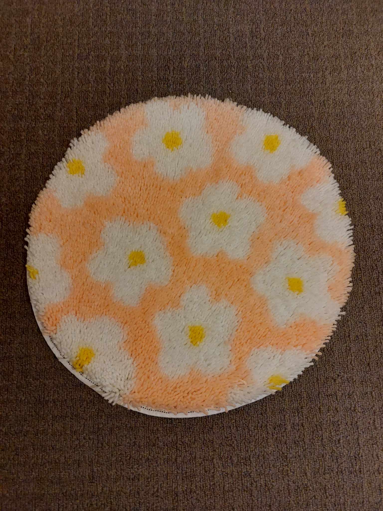 A circular pink rug with a pattern of daisies.